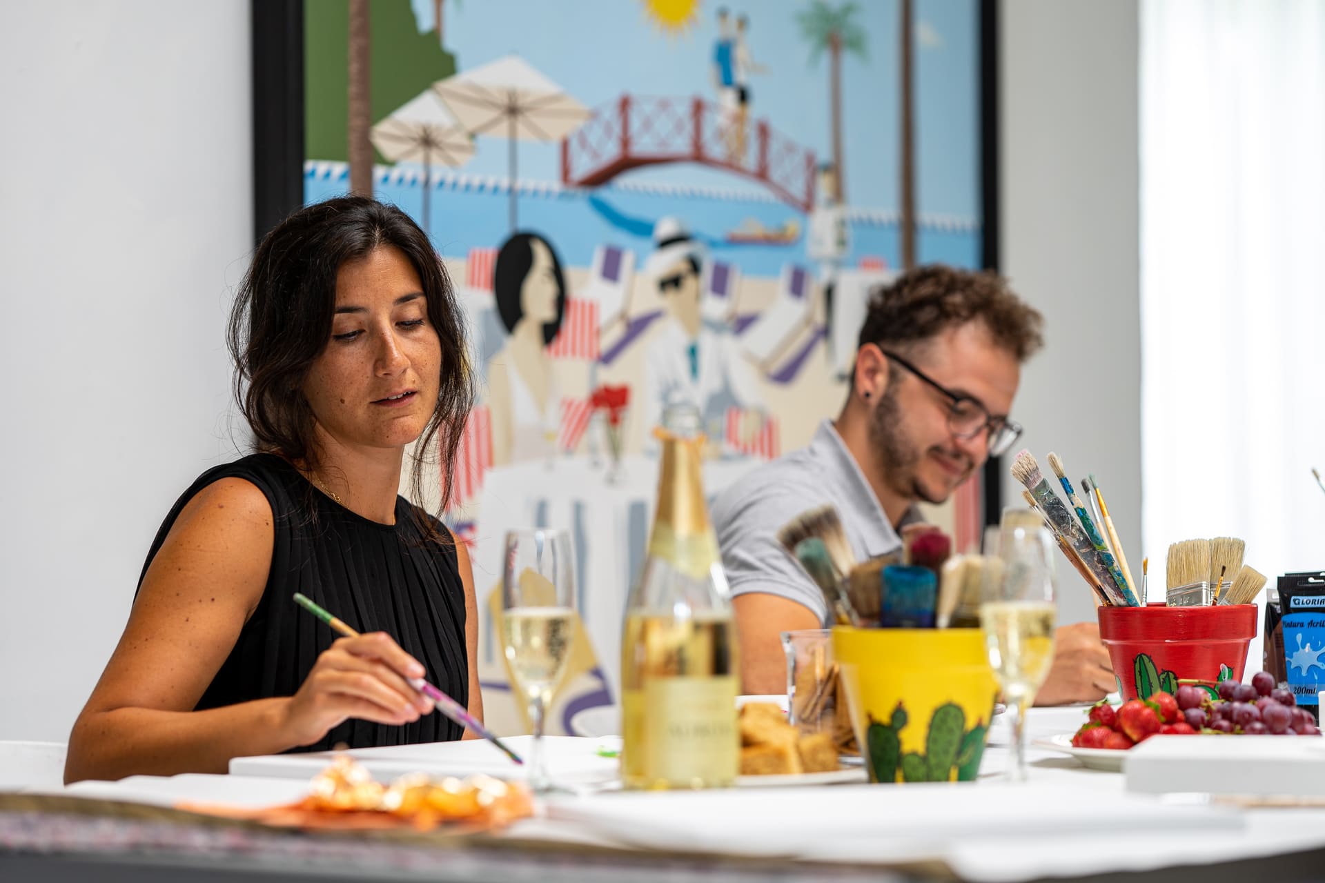 A man and a woman painting on a table with champange