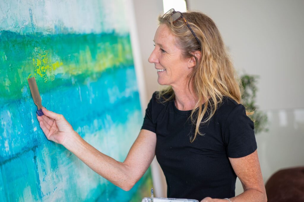 Woman painting a blue with green art piece